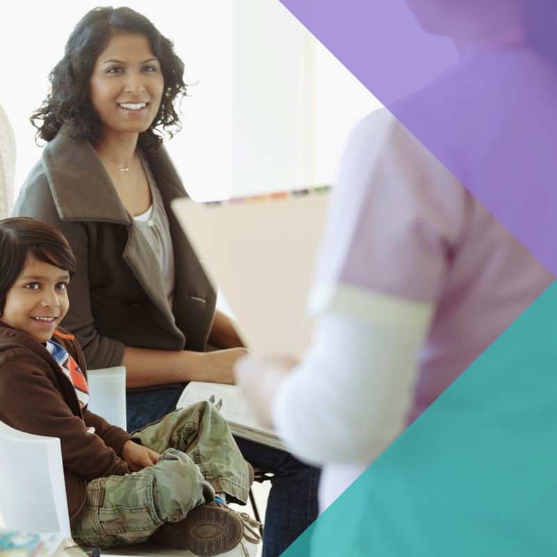 A South Asian woman and child in the background facing a health professional